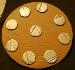 A shield made of cardboard with silver circles for rivets. 