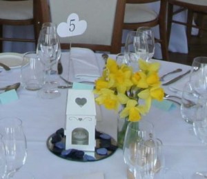 A tealight house and vase of daffodils set out on one of the tables